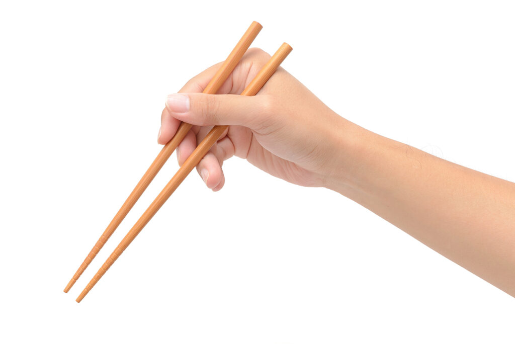 Person 's right hand using bamboo chopsticks against white background